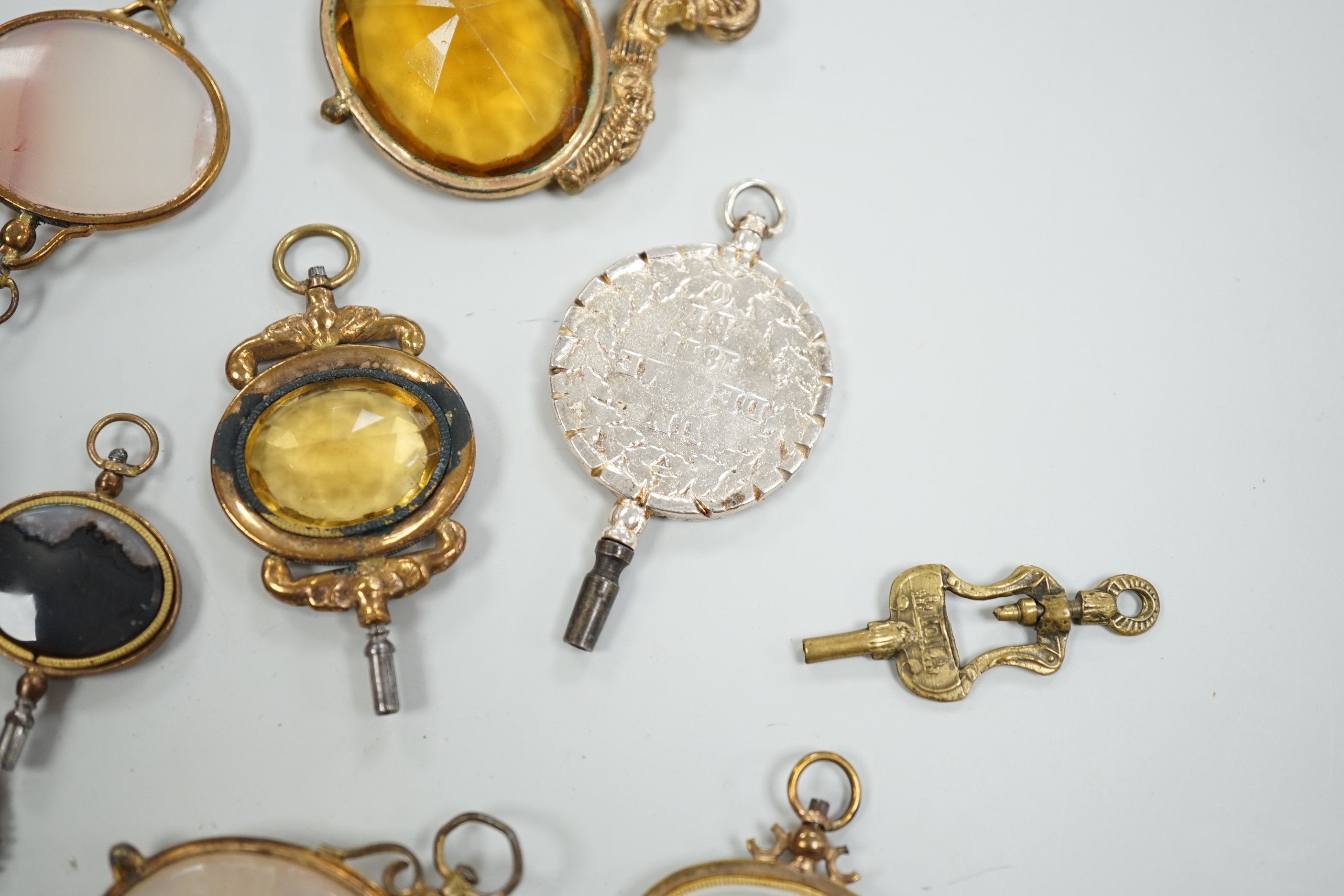 Ten assorted mainly 19th century base or yellow metal oval and gem set large watch keys, including agate and citrine paste and one set with French medallion, largest 69mm.